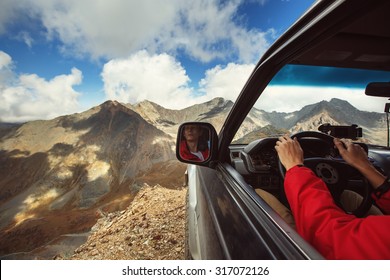 Driver In Car On The Edge Of Cliff In Wild Mountains