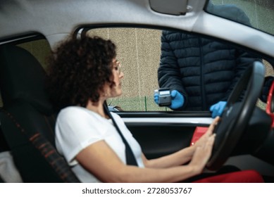 Driver in car with window down being breathalyzed by police officer at roadside sobriety checkpoint, promoting responsible driving, public safety and alcohol testing compliance