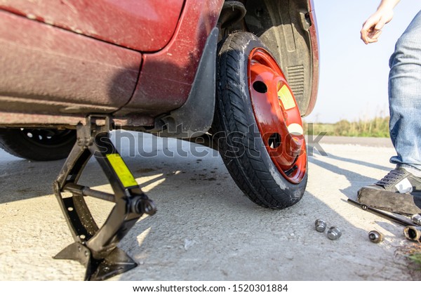 the driver changes the punctured wheel to\
a temporary one among the road,\
close-up