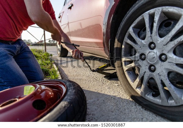 the driver changes the punctured wheel to\
a temporary one among the road,\
close-up