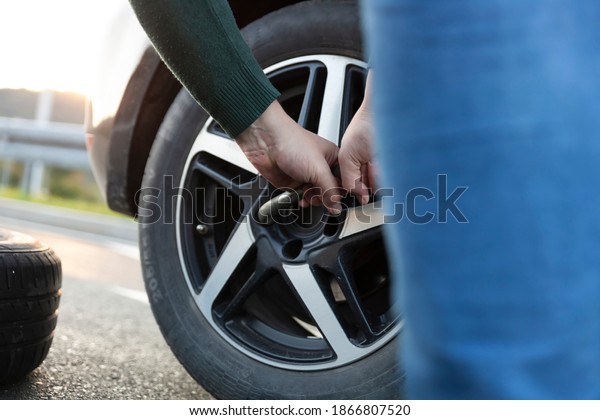 The driver changes\
the tire on the highway