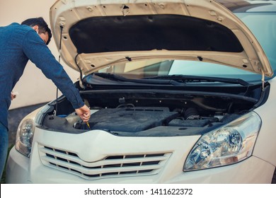 Driver check oil level in the car engine. Vehicle repair service, auto mechanic job. Young man motorist has problems, looking under his car hood for a safe driving and maintenance, preparing for road. - Shutterstock ID 1411622372