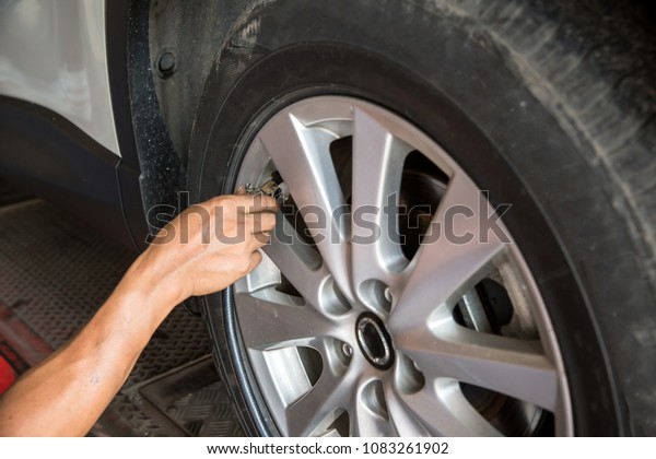 Driver checking air\
pressure and filling air in the tires close up.Technician is\
inflate car tire , car maintenance service transportation safety\
concept.