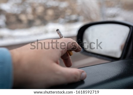 Driver with a cigarette in hands. Smoking while driving a car. Smoking cigarette in car