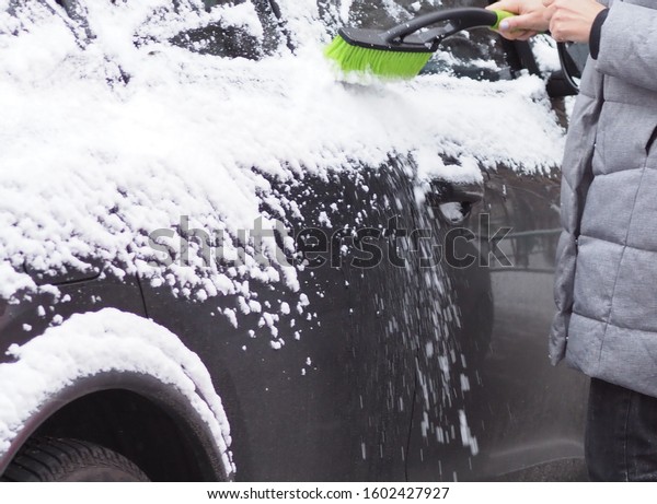 driver cleans car from\
snow