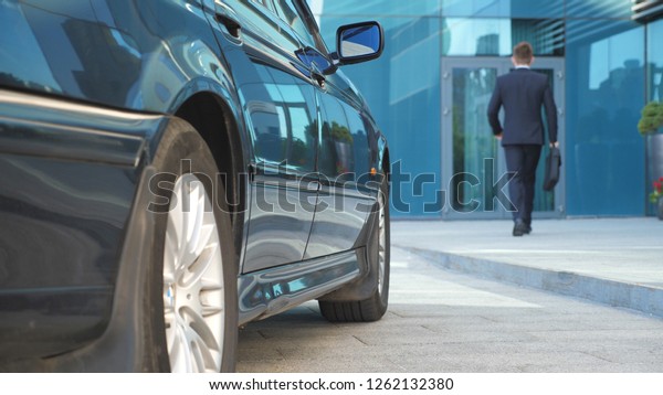 Driver coming to car and opens door for\
businessman. Chauffeur uncover door of automobile for male\
passenger. Business man with briefcase get out from auto and\
walking to office building. Slow\
Motion.