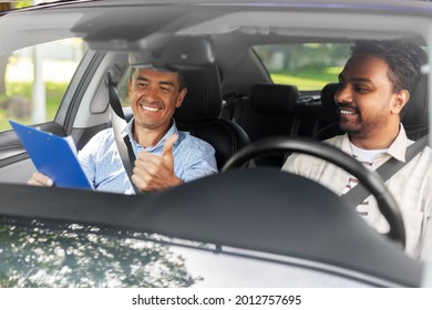 driver courses, exam and people concept - happy smiling indian man and driving school instructor with clipboard showing thumbs up in car