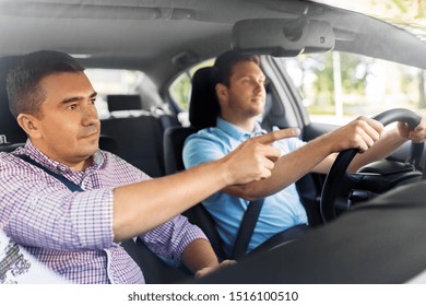 Driver Courses And People Concept - Car Driving School Instructor Teaching Young Man To Drive