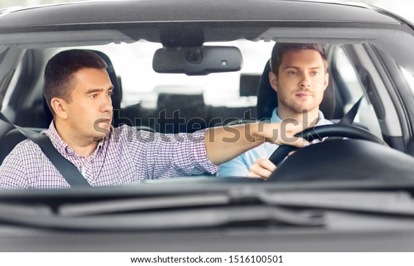 driver courses and people concept -\
car driving school instructor teaching young man to\
drive
