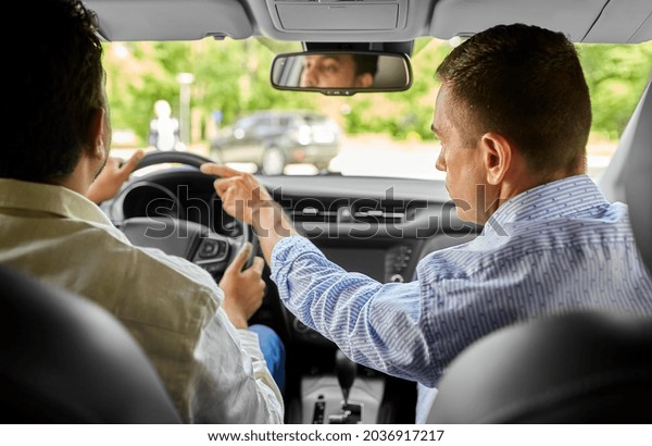 driver courses and people concept -\
car driving school instructor teaching indian man to\
drive