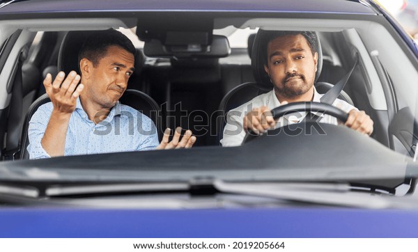 driver courses and people\
concept - driving school instructor talking to sad man failed exam\
in car