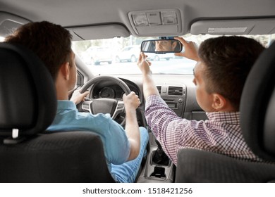 driver courses and people concept - man and driving school instructor adjusting rearview mirror in car