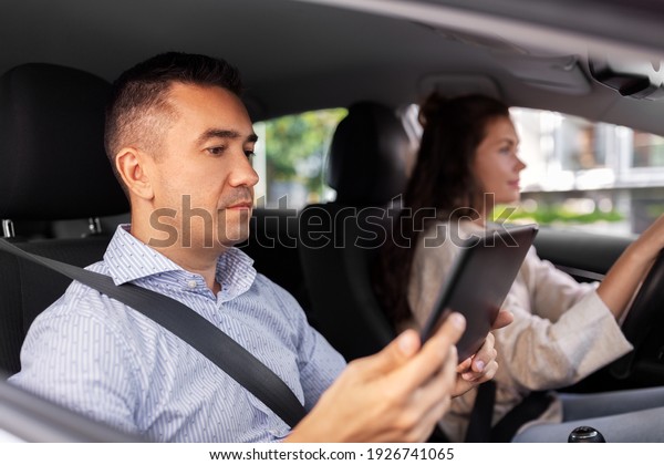 driver courses and people\
concept - woman and driving school instructor with tablet pc\
computer in car