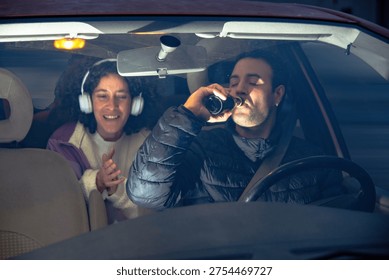 Driver drinking beer while passenger looking on happily