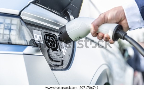 The driver of the electric car\
inserts the electrical connector to charge the\
batteries.