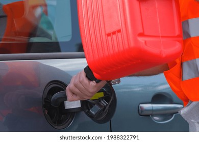 Driver fills the fuel in an empty car tank from red canister on the side of the road