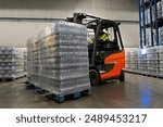 Driver in a forklift carrying two pallets of product in a warehouse