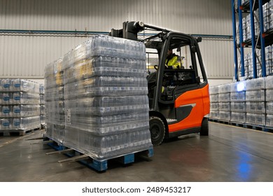 Driver in a forklift carrying two pallets of product in a warehouse - Powered by Shutterstock