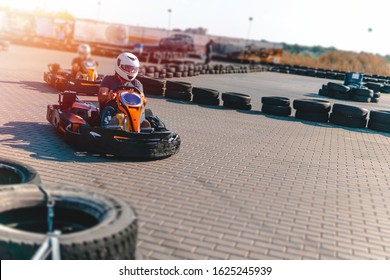 A driver in gear and helmet drives a racing car. In action. Go karts racing, sreet karting, rent. extreme sport. fun entertainment for drivers. Soft light glow, copy space