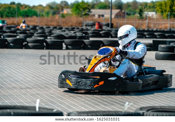 A driver in gear and helmet drives a racing car.\
In action. Go karts racing, sreet karting, rent. extreme sport. fun\
entertainment for drivers