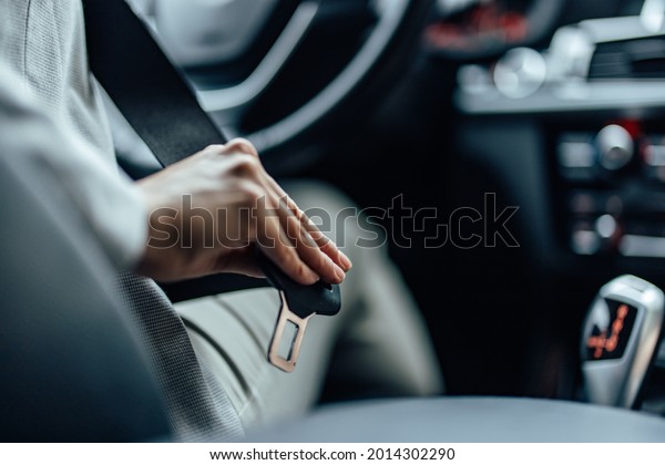 A driver, getting ready to start a drive by putting a\
seat belt on.