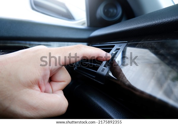 The driver hand adjust the wind speed of the car air\
vent in a car