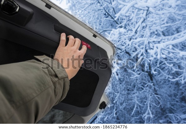 A\
driver hand opening a car boot, winter outdoor\
shot