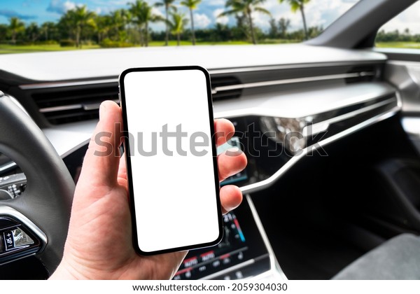 Driver hand\
using smartphone in car. Smartphone in a car use for Navigate or\
GPS. Mobile phone with isolated white screen. Blank empty screen.\
copy space. Empty space for\
text.