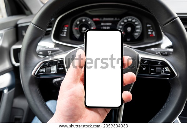 Driver hand\
using smartphone in car. Smartphone in a car use for Navigate or\
GPS. Mobile phone with isolated white screen. Blank empty screen.\
copy space. Empty space for\
text.