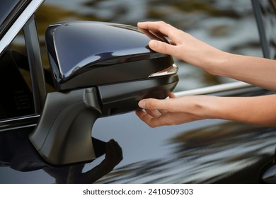 Driver hands adjusting side view mirror of a car