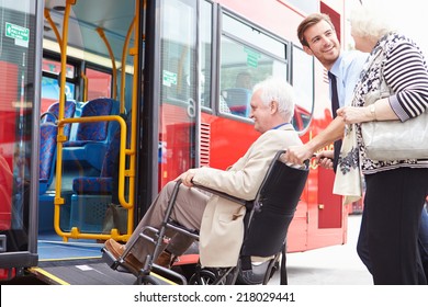 Driver Helping Senior Couple Board Bus Via Wheelchair Ramp