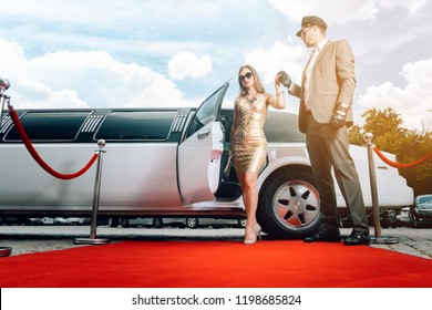 Driver Helping VIP Woman Or Star Out Of Limo On Red Carpet To A Reception 