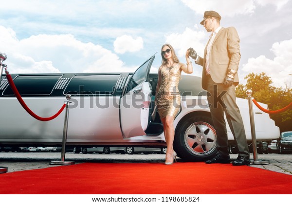 Driver helping VIP woman or star out of limo on red
carpet to a reception 