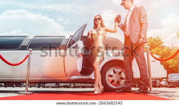 Driver helping VIP woman or star out of limo on\
red carpet