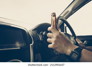 A driver holding alcoholic bottle while driving - Drunk driving concept