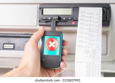 Driver holding a digital tachograph reader with big red cross mark on the screen. Tachograph download. Control.