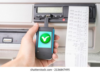 Driver holding a digital tachograph reader with a green OK check mark. Tachograph download. Control.