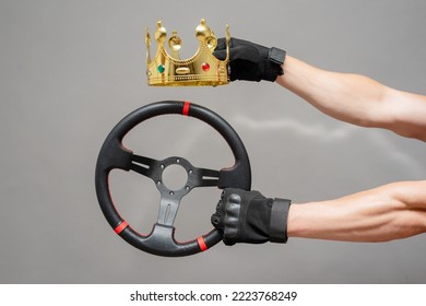 A driver is holding a golden king crown above the car steering wheel on the gray background. Racing champion concept. Win the car race concept. Egoist driver. - Shutterstock ID 2223768249