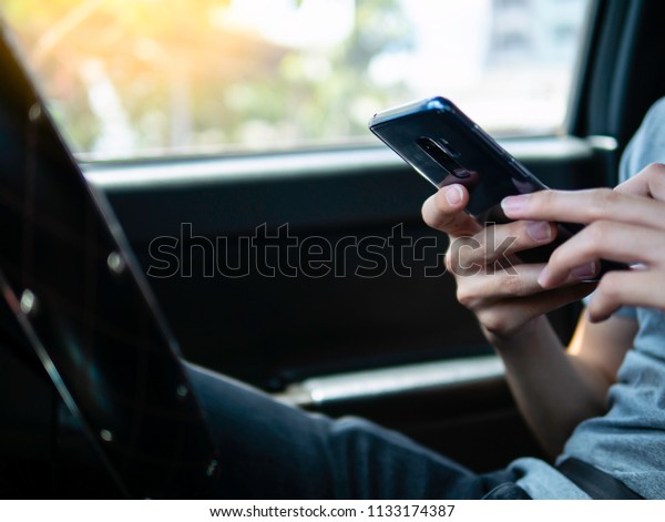Driver holding smartphone in hand, use smart\
phone while stopping. browsing, call, typing, texting, searching or\
internet connection. Steering wheel interior right-hand drive car\
in background.