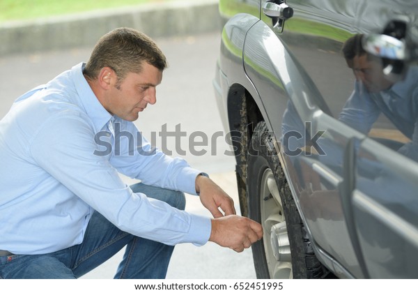 driver inspecting the\
tire