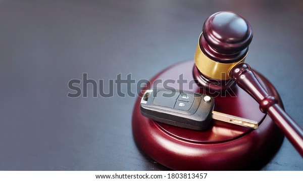 Driver license revocation concept next to the\
judge hammer. Traffic violation concept by car next to judge\
hammer. Revocable trust on a dark\
desk.