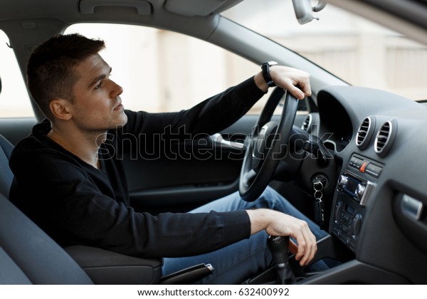 driver\
of a man in a black T-shirt is sitting in the\
car