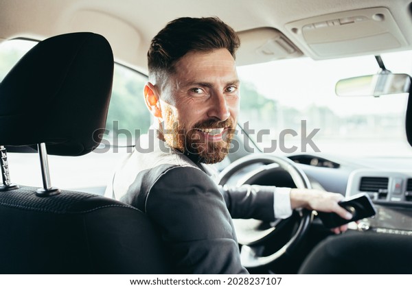 The driver of a man in a business suit looks at\
the camera