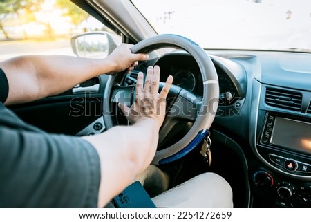 Driver man honking car horn. Close-up of driver honking car horn. Hand of angry driver honking car horn. Concept of impatient driver honking car horn 商業照片 © 