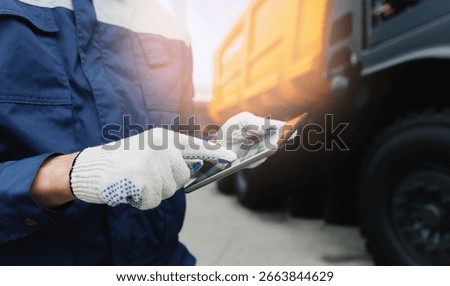 Driver man in uniform with tablet computer controls Dump truck. Concept banner automated logistics online internet.