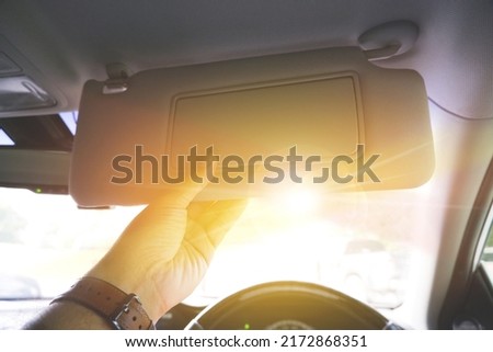 Driver manually adjusting the sun visor in order to block sunlight in a car