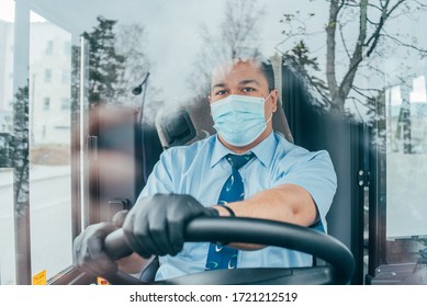 driver in mask looks at road while driving. young latin man bus driver in blue shirt has blue medical protection mask and black  gloves on hands.  bus driver wants to prevent  infection of covid 19.
