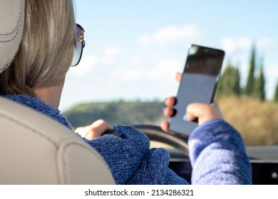 Driver With Mobile Phone In Hand. A Woman Is Talking On A Mobile Phone In The Car. The Concept Of Safe Driving. A Woman Driving Texts. Dangerous Use Of A Mobile Phone While Driving.