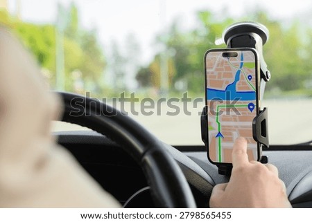 Driver navigating with smartphone GPS map displayed on dashboard mount, modern vehicle technology for travel and direction