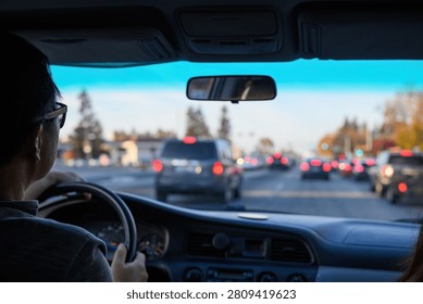 Driver navigating through urban traffic, keeping safe following distance. Red brake lights from vehicles ahead. California. USA.